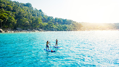 Buy stock photo Couple, paddle board and ocean in summer, adventure and drone on holiday, island and outdoor in sunshine. People, man and woman on vacation to relax in tropical water, journey and sea in Malaysia