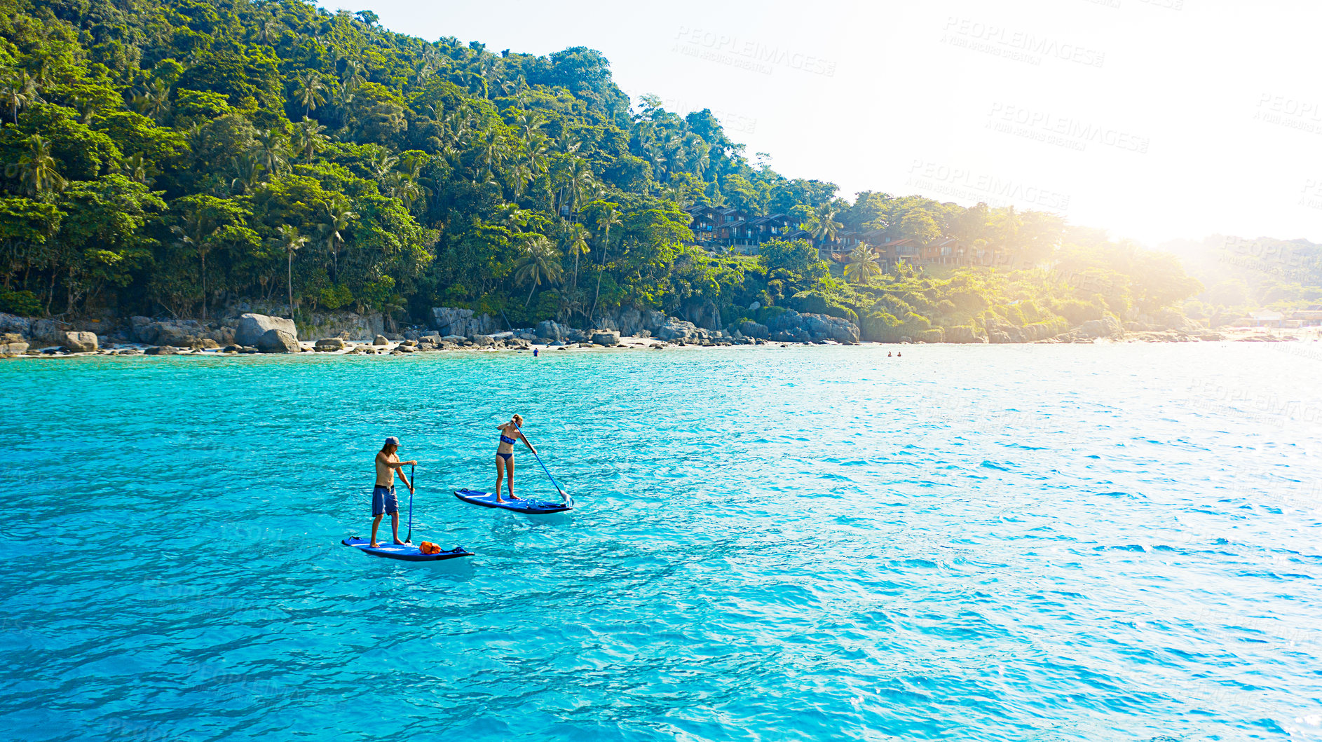 Buy stock photo Couple, paddle board and ocean in summer, outdoor and drone on holiday, island and adventure in sunshine. People, man and woman on vacation to relax in tropical water, journey and sea in Malaysia