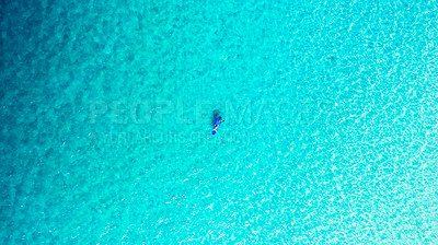 Buy stock photo High angle shot of a man paddle boarding across the sea