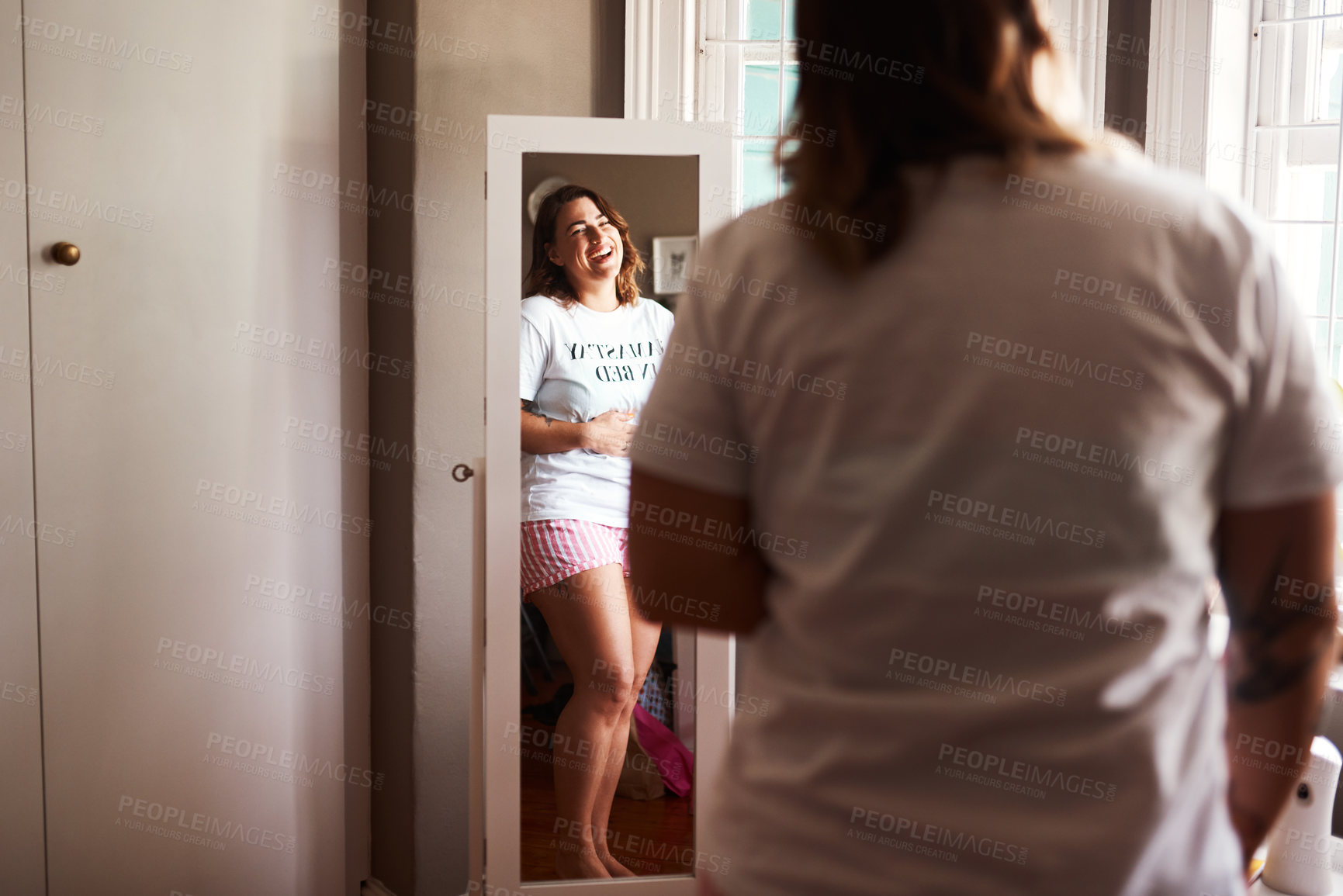 Buy stock photo Shot of a young woman looking at herself in the mirror