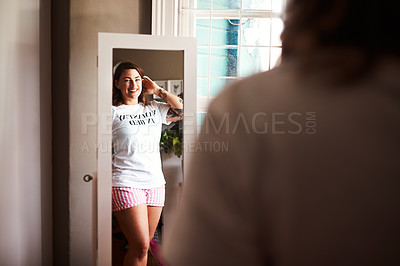 Buy stock photo Shot of a young woman looking at herself in the mirror