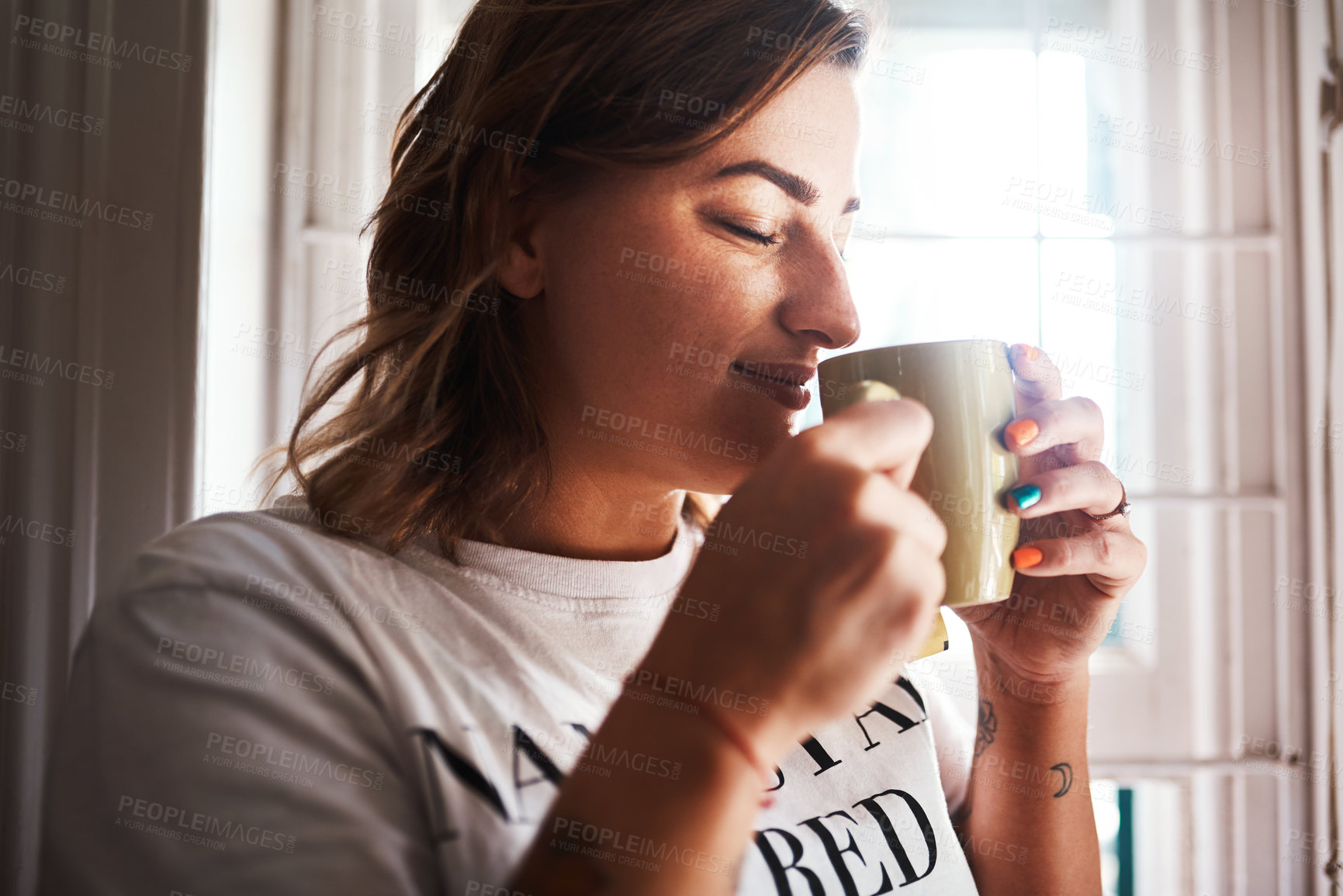 Buy stock photo Cropped shot of a beautiful young woman having coffee at home