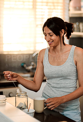 Buy stock photo Shot of a young woman making a cup of tea at home