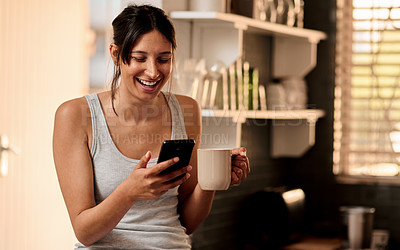 Buy stock photo Shot of a young woman using a smartphone while enjoying a cup of coffee at home