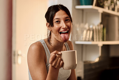 Buy stock photo Shot of a young woman enjoying a playful moment while having a cup of coffee at home