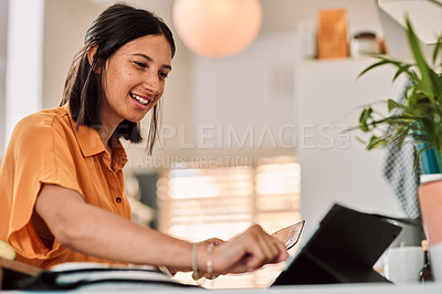 Buy stock photo Shot of a happy young woman using a digital tablet while preparing a meal at home