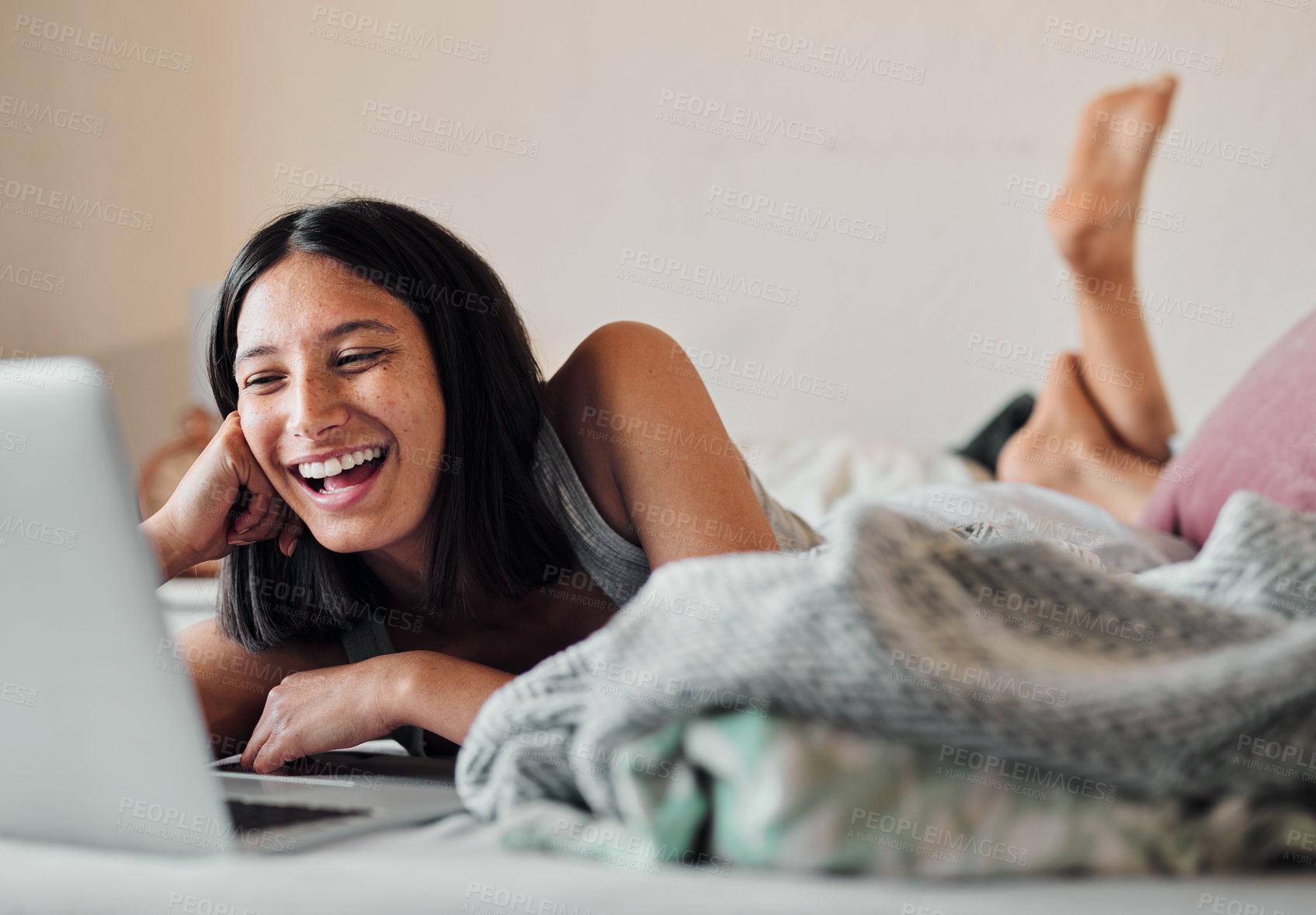 Buy stock photo Shot of a young woman using a laptop while relaxing in bed at home