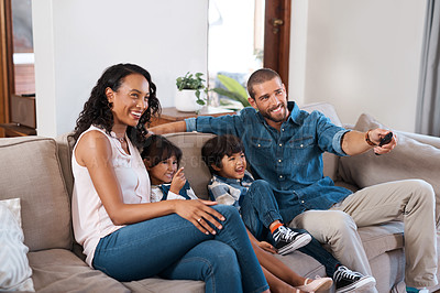 Buy stock photo Shot of a couple watching something on the television with their two young kids