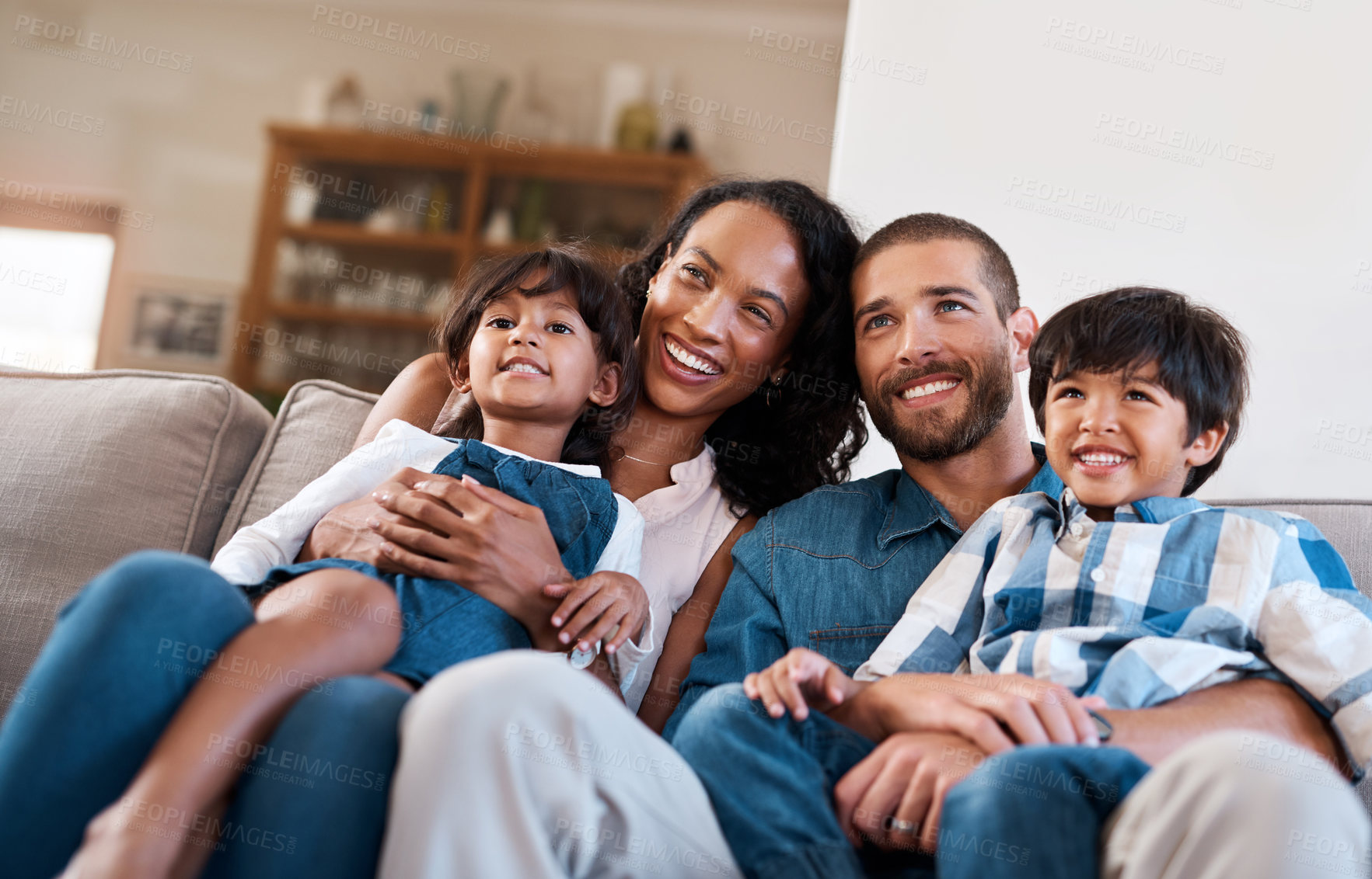 Buy stock photo Cropped shot of a family of four sitting together on the sofa at home