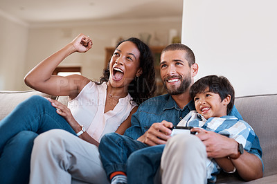 Buy stock photo Shot of a man playing video games while relaxing at home with his wife and son