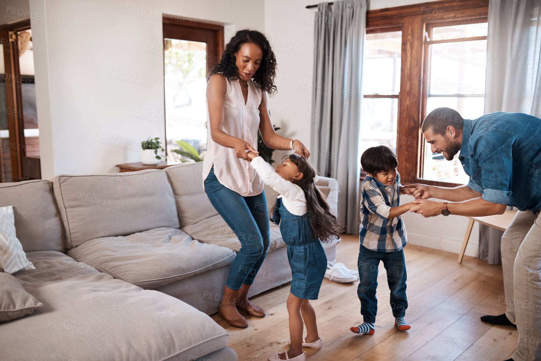 Buy stock photo Shot of a family of four dancing together at home