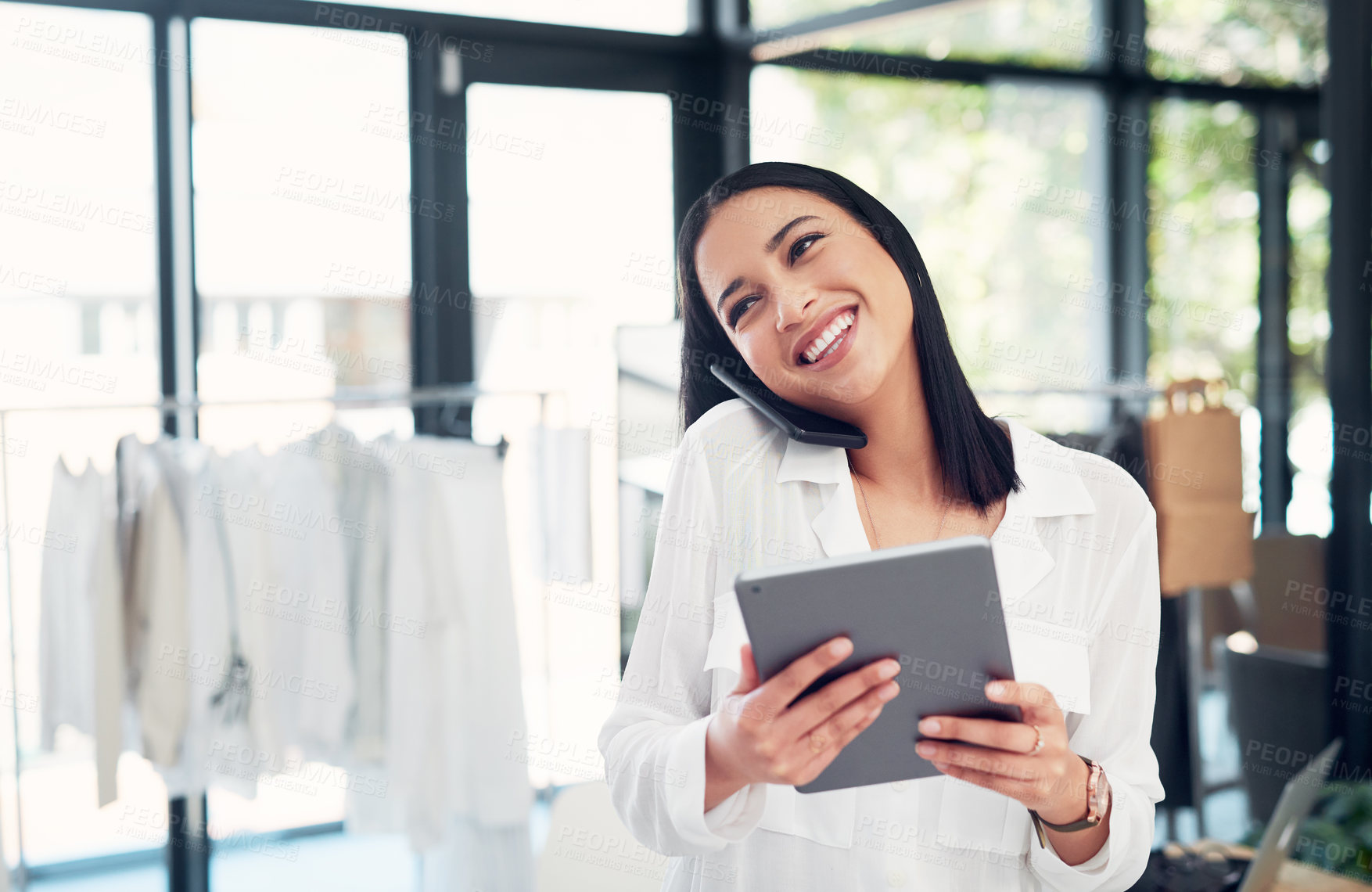 Buy stock photo Shot of a young business owner talking on her cellphone while using a digital tablet in her store