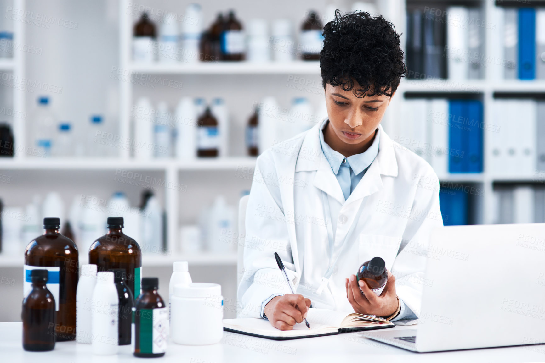 Buy stock photo Shot of a young scientist writing notes while working in a lab