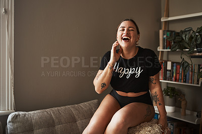 Buy stock photo Cropped shot of an attractive young woman laughing while sitting on her couch at home