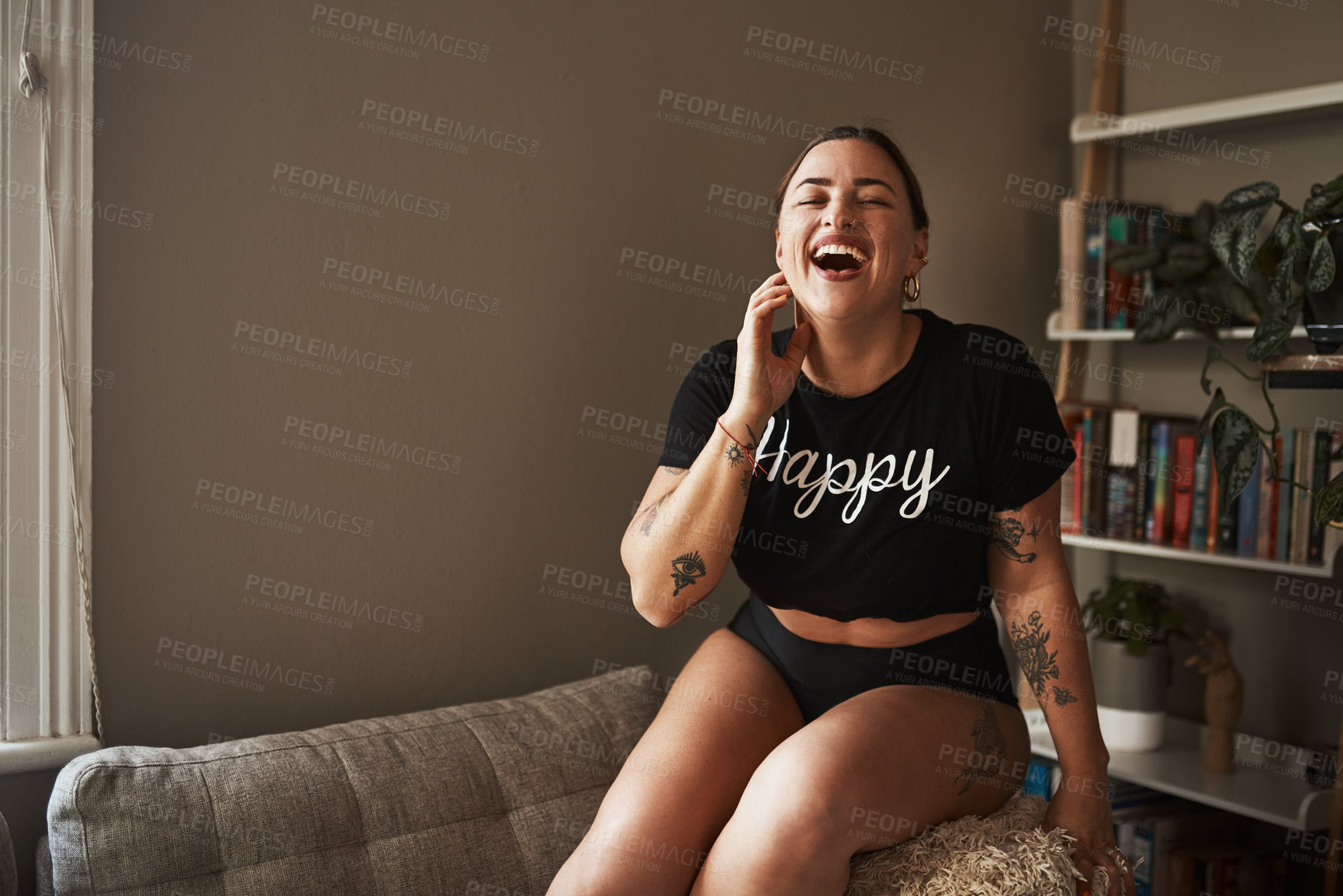 Buy stock photo Cropped shot of an attractive young woman laughing while sitting on her couch at home