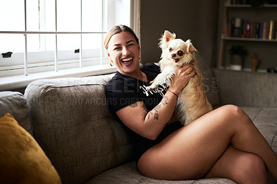 Buy stock photo Cropped portrait of an attractive young woman smiling while holding her dog in her living room at home