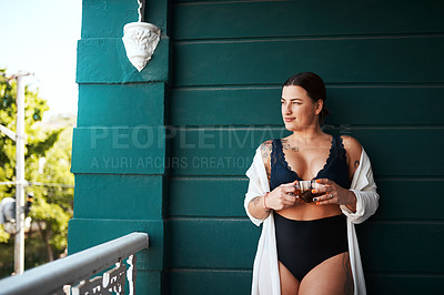 Buy stock photo Cropped shot of an attractive young woman looking away thoughtfully while holding a glass of tea outdoors at home