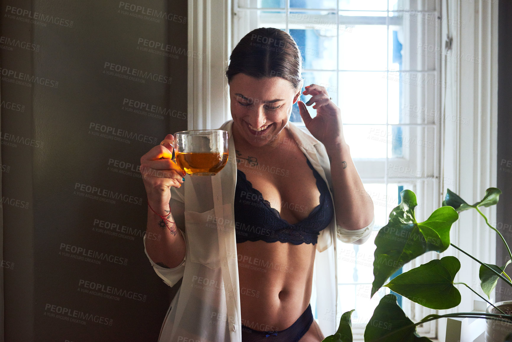 Buy stock photo Cropped shot of an attractive young woman smiling while holding a glass of tea in the morning at home