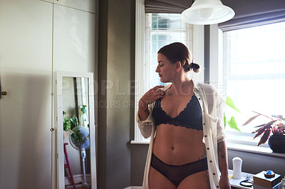 Buy stock photo Cropped shot of an attractive young woman analyzing herself while standing in front of the in the mirror in her bedroom at home