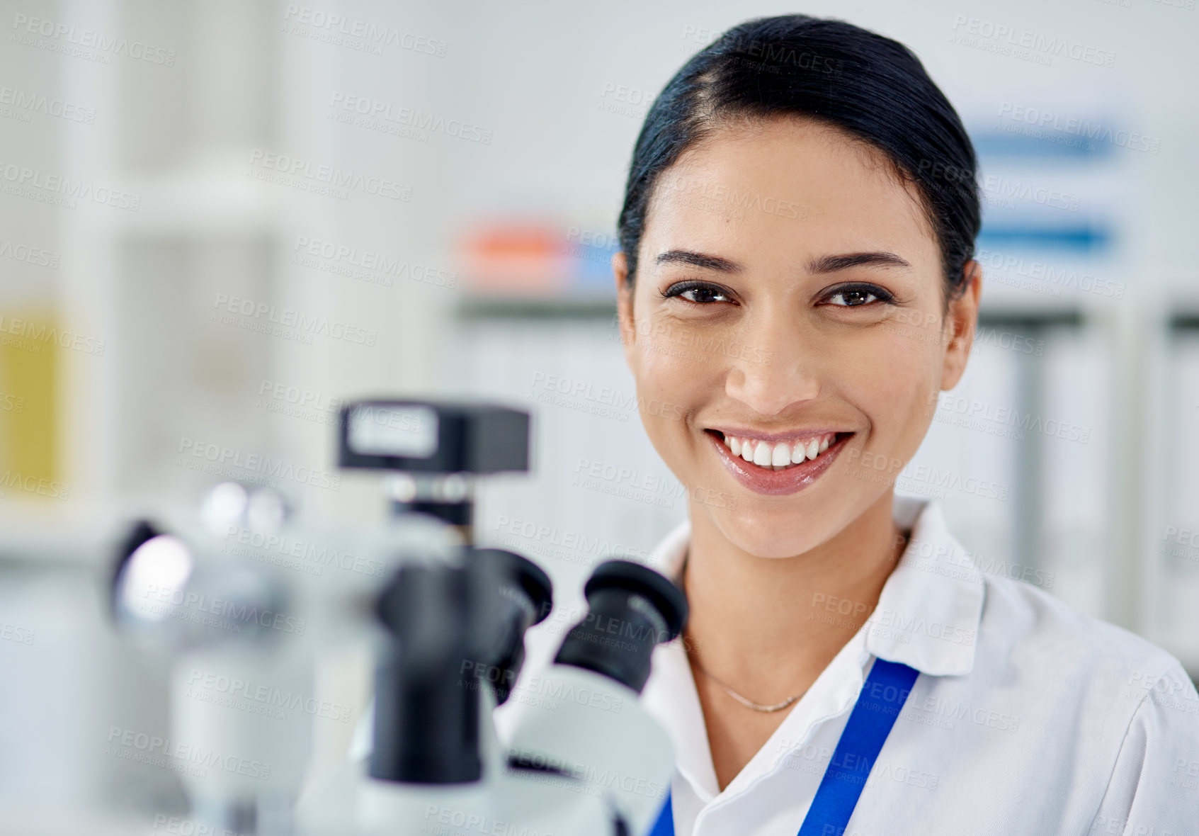 Buy stock photo Portrait of a young scientist using a microscope in a laboratory