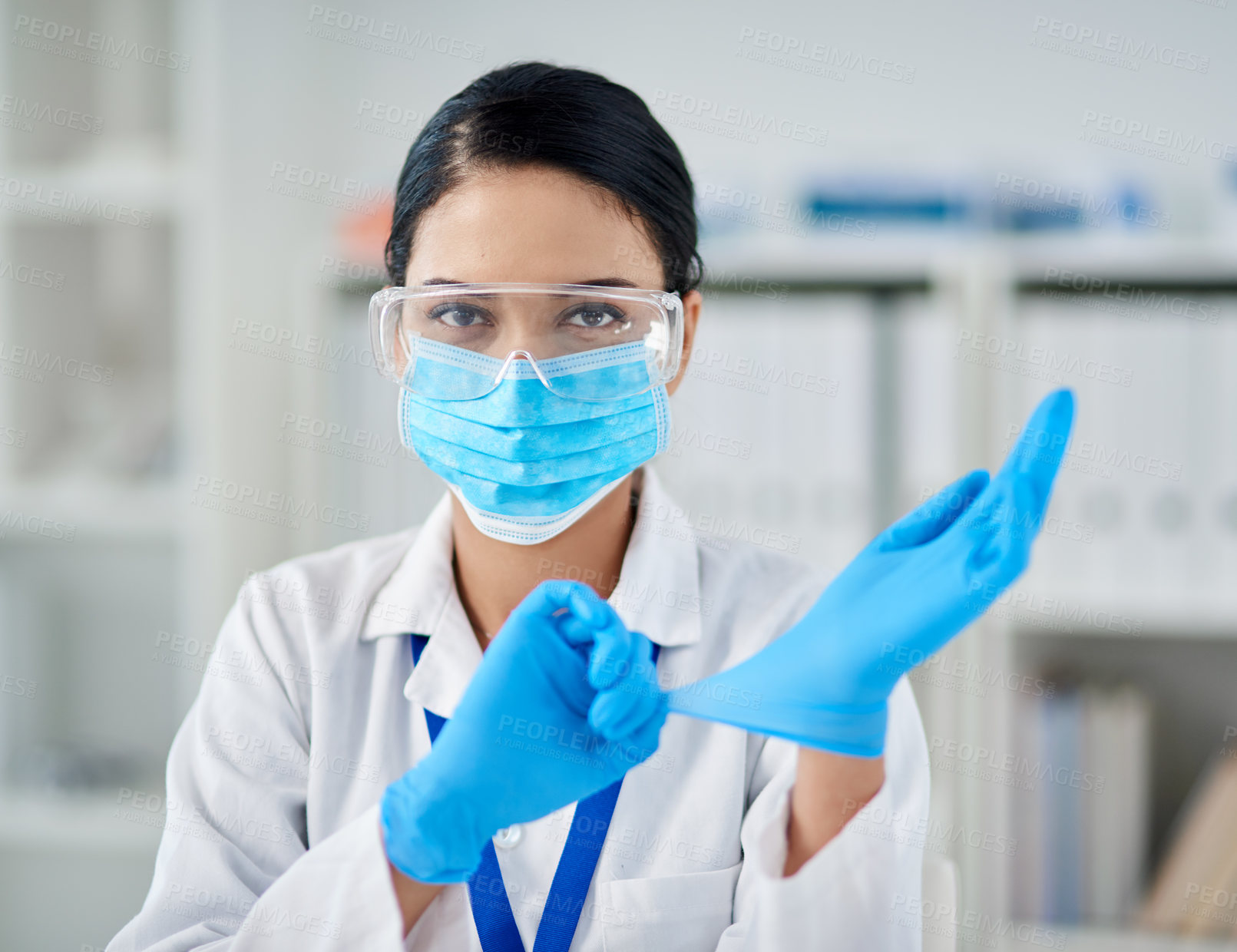 Buy stock photo Portrait of a confident young woman putting on surgical gloves in a laboratory