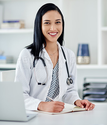 Buy stock photo Shot of a young doctor writing in a notebook at her desk