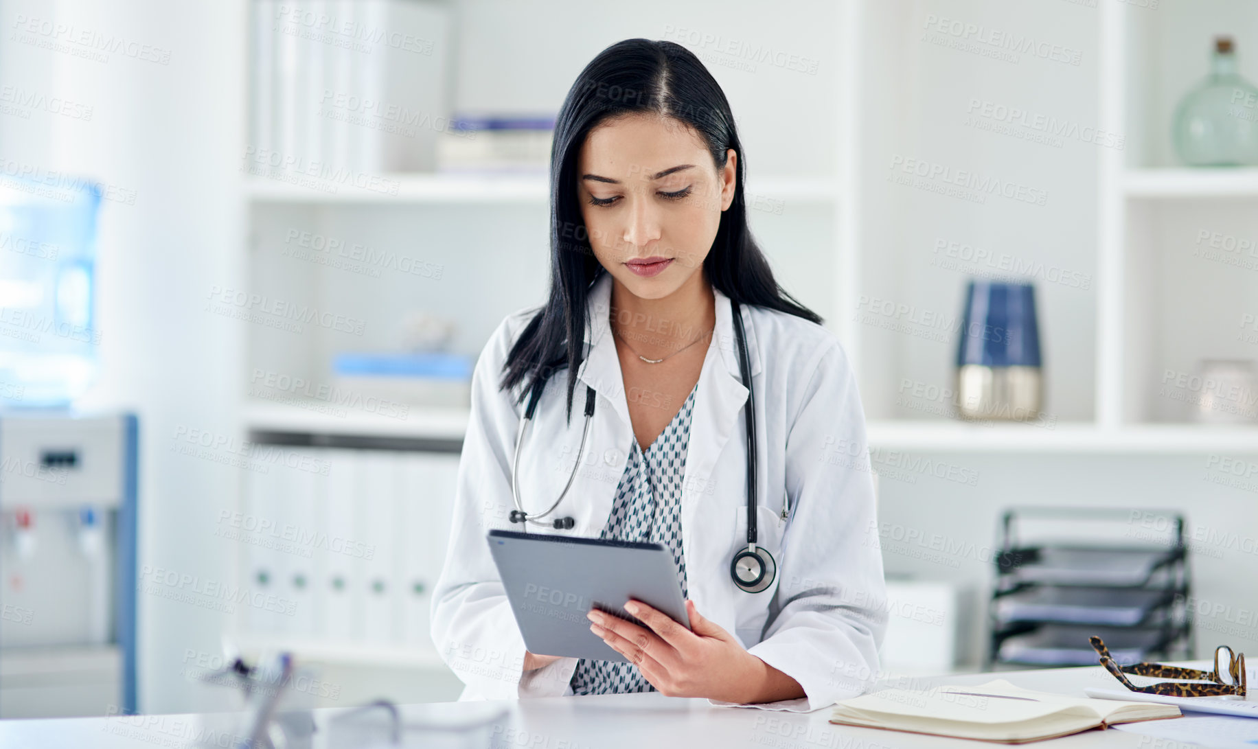 Buy stock photo Shot of a young doctor using a digital tablet while working in a clinic