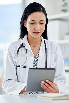 Buy stock photo Shot of a young doctor using a digital tablet while working in a clinic