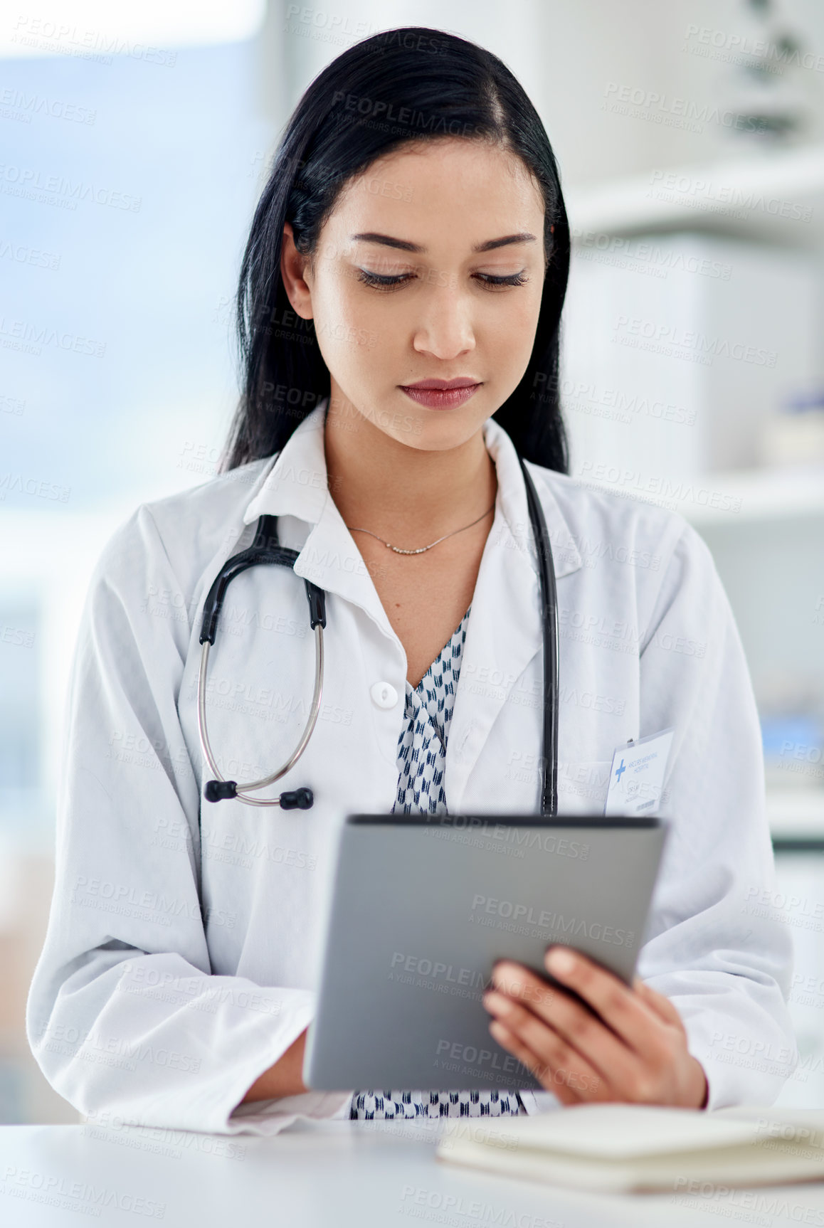 Buy stock photo Shot of a young doctor using a digital tablet while working in a clinic