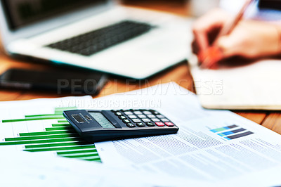 Buy stock photo Cropped shot of an unrecognizable businesswoman sitting and writing in a notebook after calculating her finances