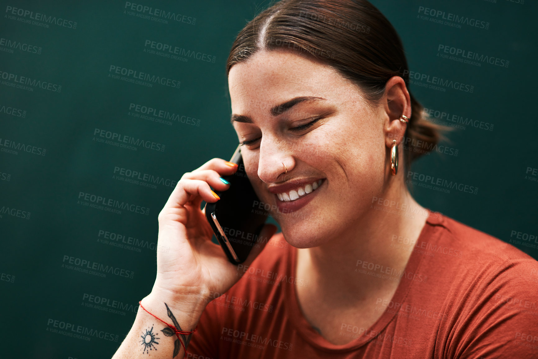 Buy stock photo Cropped shot of an attractive young businesswoman sitting alone against a green background and using her cellphone