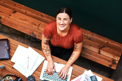 Buy stock photo High angle portrait of an attractive young businesswoman sitting alone and blogging on her laptop