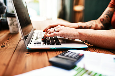 Buy stock photo Cropped shot of an unrecognizable businesswoman sitting alone at her desk and typing on her laptop