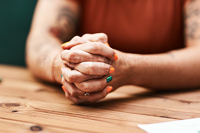 Buy stock photo Cropped shot of an unrecognizable businesswoman sitting alone at her desk with her hands clasped together
