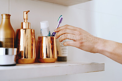 Buy stock photo Cropped shot of of an unrecognizable woman taking out a toothbrush from her bathroom cabinet