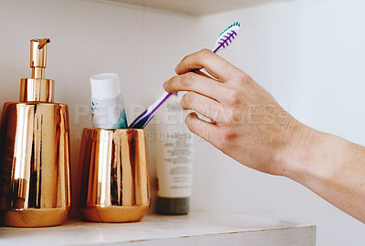 Buy stock photo Cropped shot of of an unrecognizable woman taking out a toothbrush from her bathroom cabinet