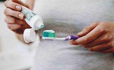 Buy stock photo Cropped shot of an unrecognizable woman squeezing toothpaste onto her toothbrush at home