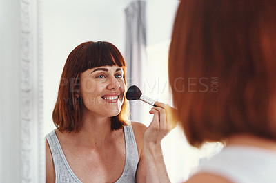 Buy stock photo Shot of an attractive young woman applying makeup on her face inside her bathroom at home