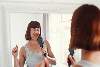 Buy stock photo Shot of an attractive young woman holding a hairbrush and singing in her bathroom at home