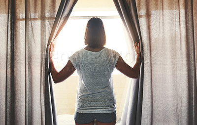 Buy stock photo Rearview shot of a woman opening the curtains inside her bedroom at home in the morning