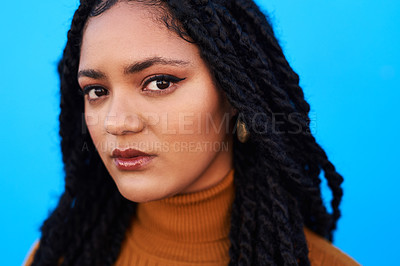 Buy stock photo Cropped shot of a beautiful young woman posing against a blue wall