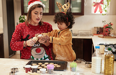 Buy stock photo Cropped shot of a cheerful young woman and her son baking cookies together in the kitchen during christmas time at home