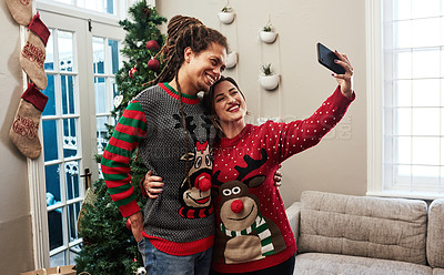 Buy stock photo Cropped shot of a cheerful young couple taking a self portrait together at home during christmas time