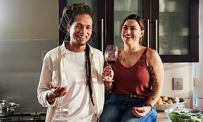 Buy stock photo Portrait of a cheerful young couple enjoying a glass of wine together while standing in the kitchen at home