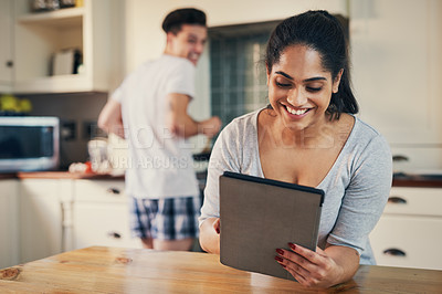Buy stock photo Shot of a young woman using a digital tablet while her boyfriend stands in the background