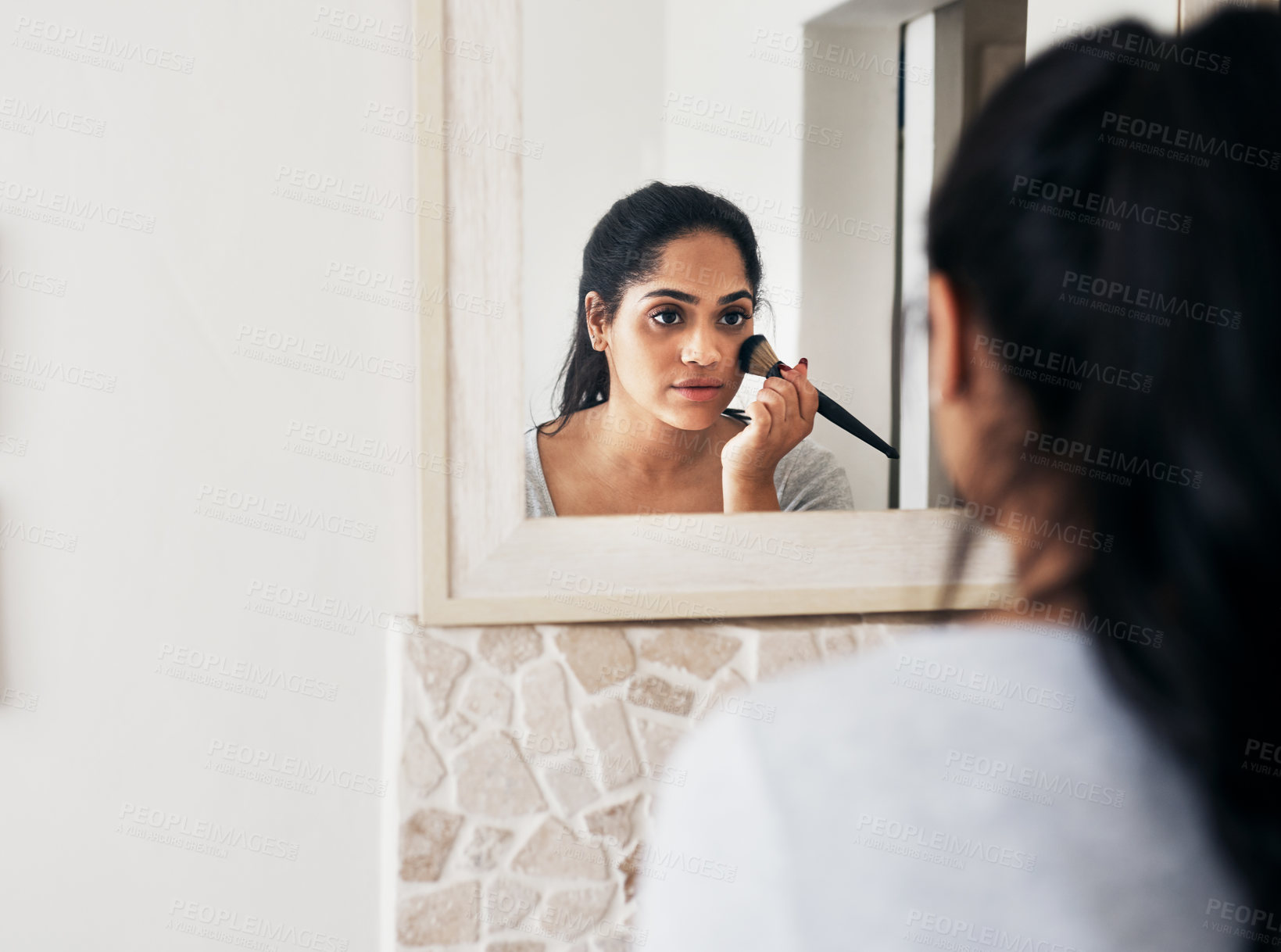 Buy stock photo Cropped shot of a young woman applying makeup while looking into her bathroom mirror