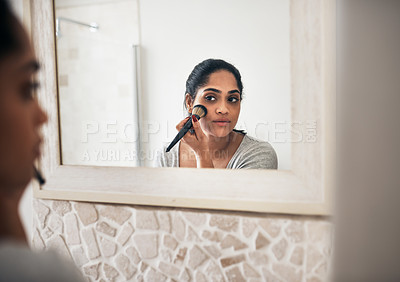 Buy stock photo Cropped shot of a young woman applying makeup while looking into her bathroom mirror