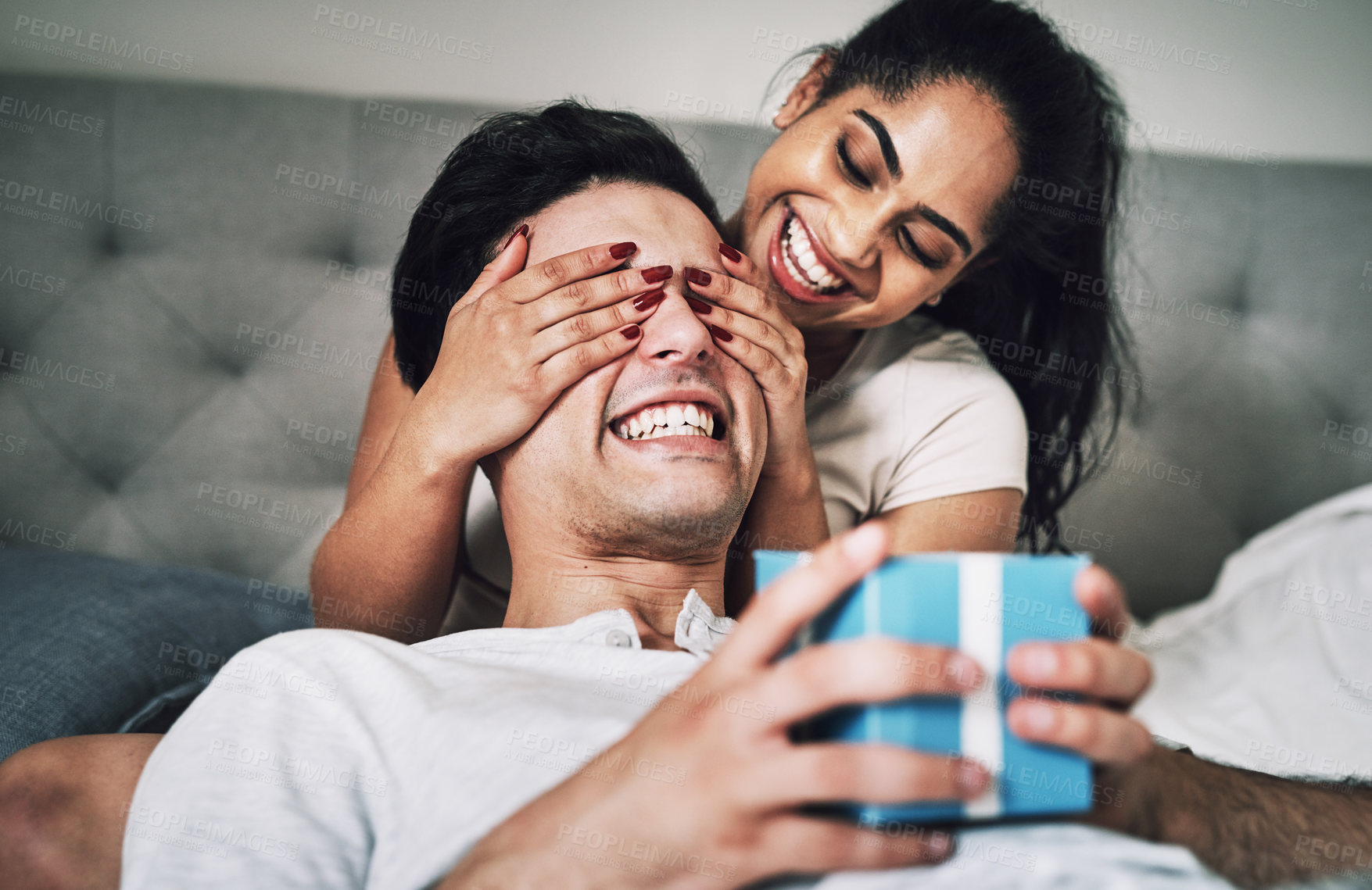 Buy stock photo Shot of a woman covering her boyfriend's eyes while surprising him with a gift