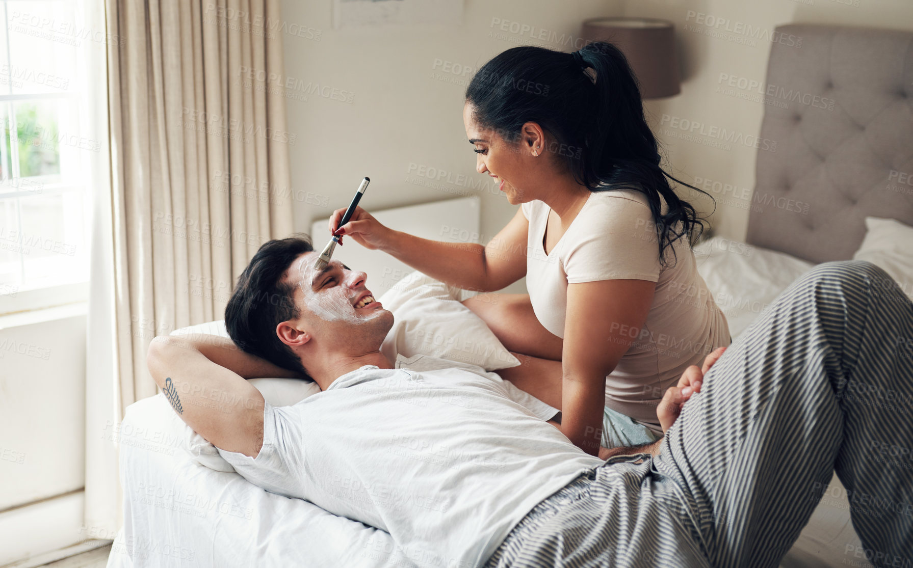 Buy stock photo Shot of a young woman giving her boyfriend a facial at home