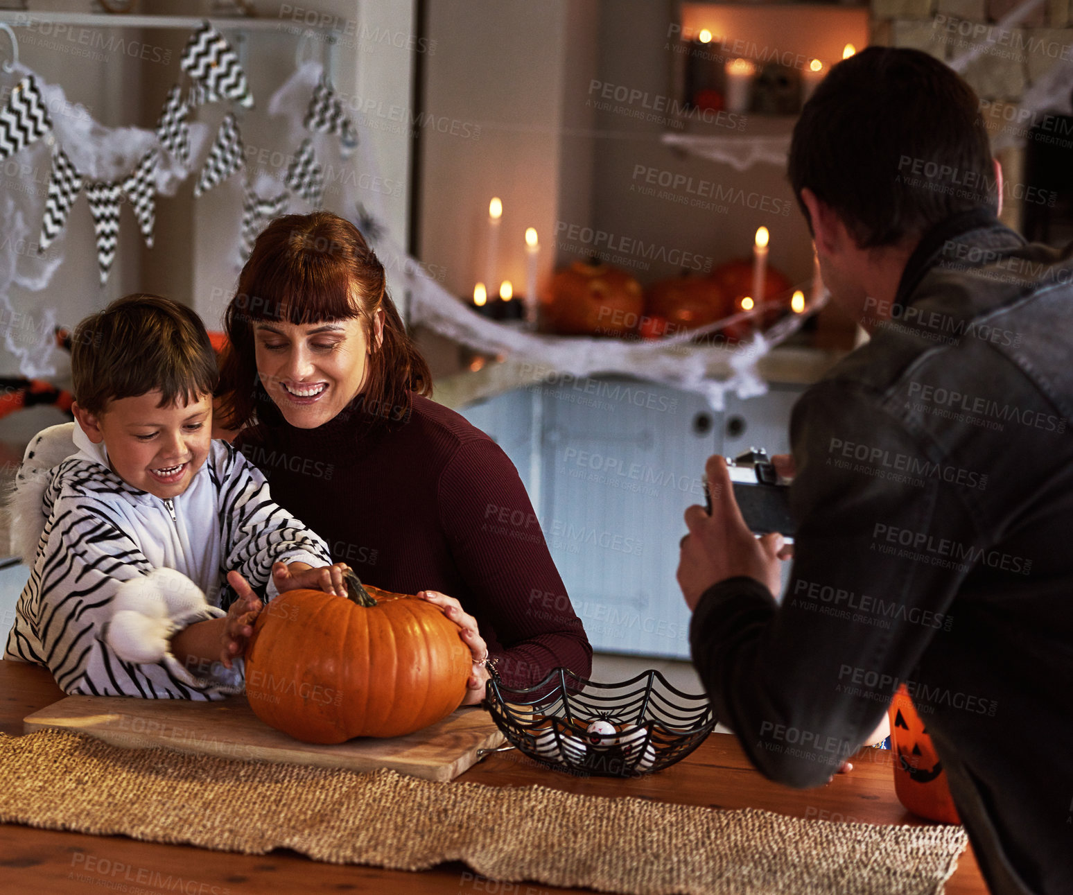 Buy stock photo Pictures, parents or kid with pumpkin for halloween to celebrate with smile, son or boy for fun. Home, man or woman with child carving face in vegetable for holiday lantern, decor or family memory